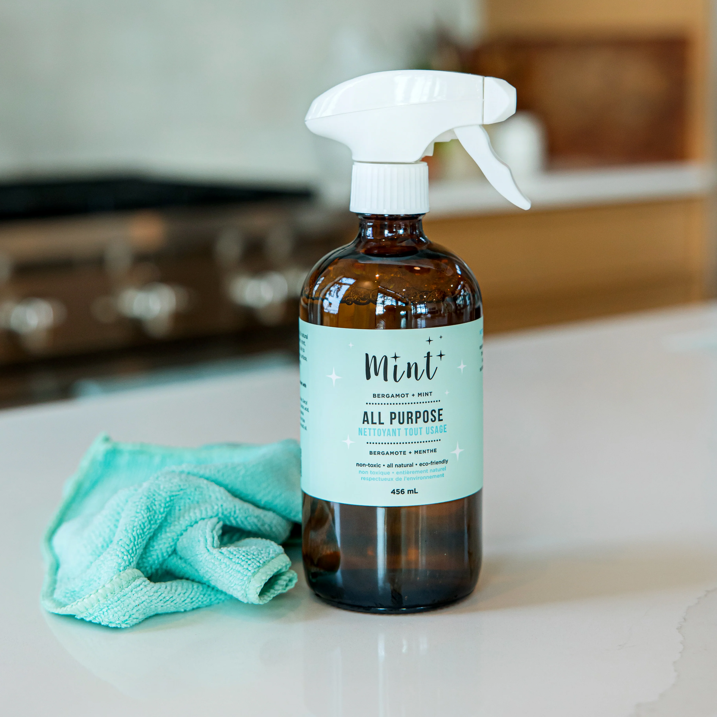 brown bottle of all purpose cleaner by mint cleaning on counter with microfiber cloth beside