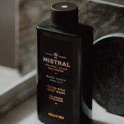 Black bottle of Mistral Black Amber Extra-Rich Body Wash on a bathroom counter.