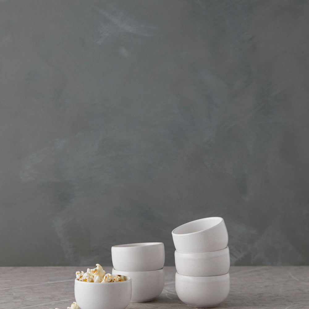 Set of white ceramic bowls on a gray surface with a dark gray background