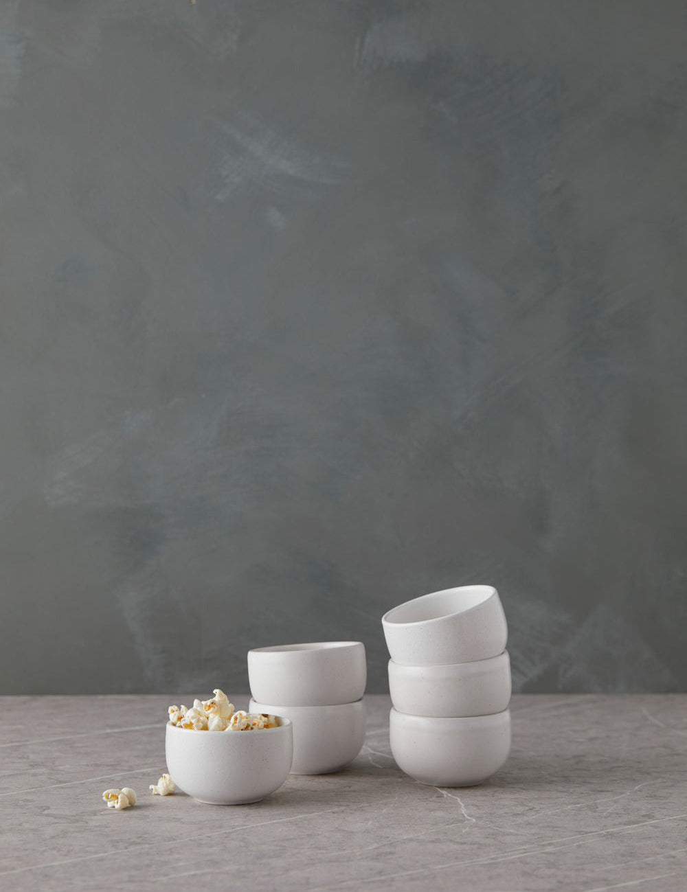 Set of white ceramic bowls on a gray surface with a dark gray background