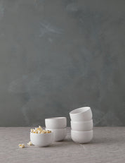 Set of white ceramic bowls on a gray surface with a dark gray background
