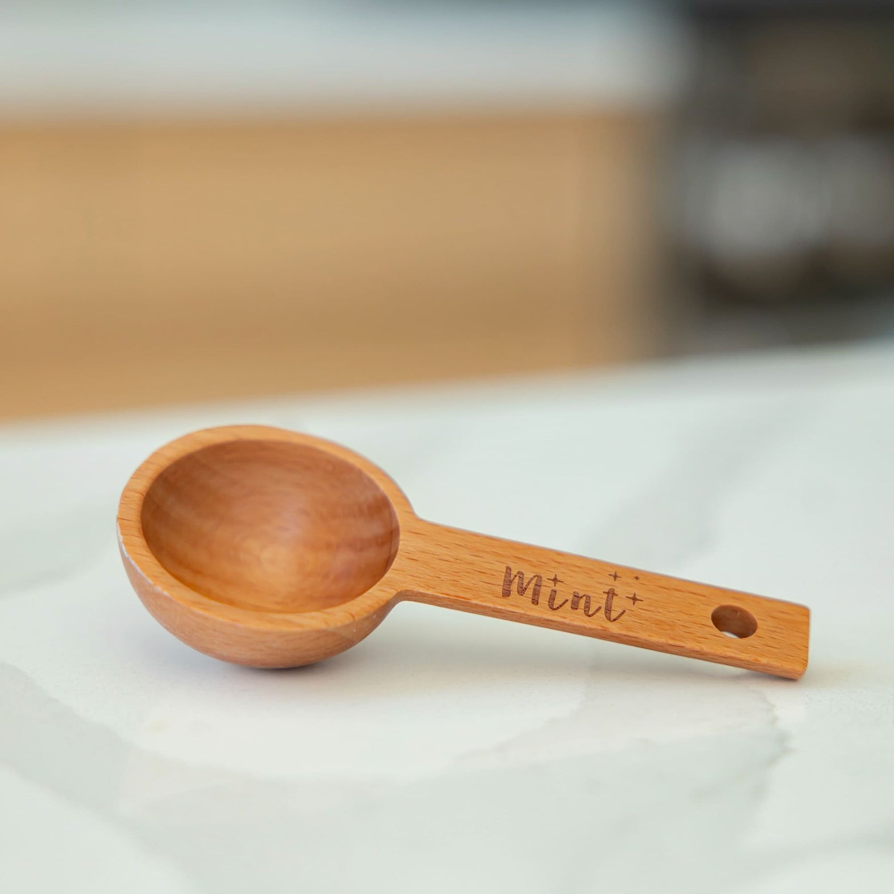 Wooden measuring spoon with 'Mini' engraving on a white surface
