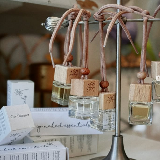Car diffusers by get naked essentials hanging on a metal rack with wooden accents