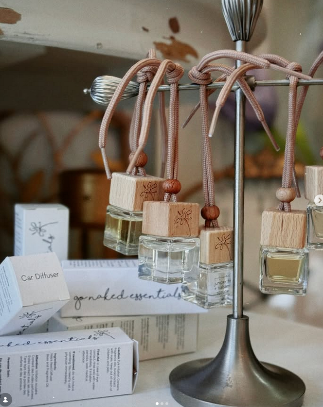 Car diffusers by get naked essentials hanging on a metal rack with wooden accents