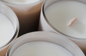 Close-up of three white candles in glass containers with a blurred background