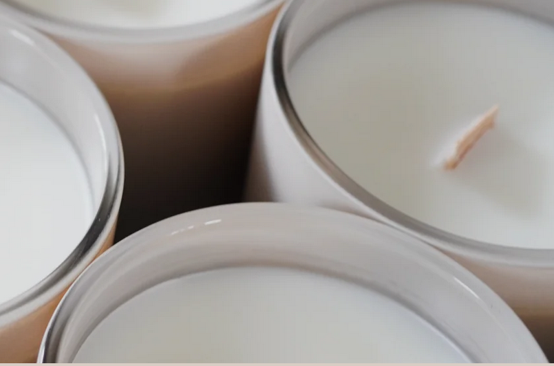 Close-up of three white candles in glass containers with a blurred background