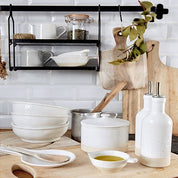 Kitchen counter with white ceramic bowls, a wooden spoon, and a black shelf with kitchen items.