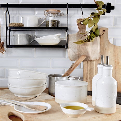 Kitchen counter with white ceramic bowls, a wooden spoon, and a black shelf with kitchen items.
