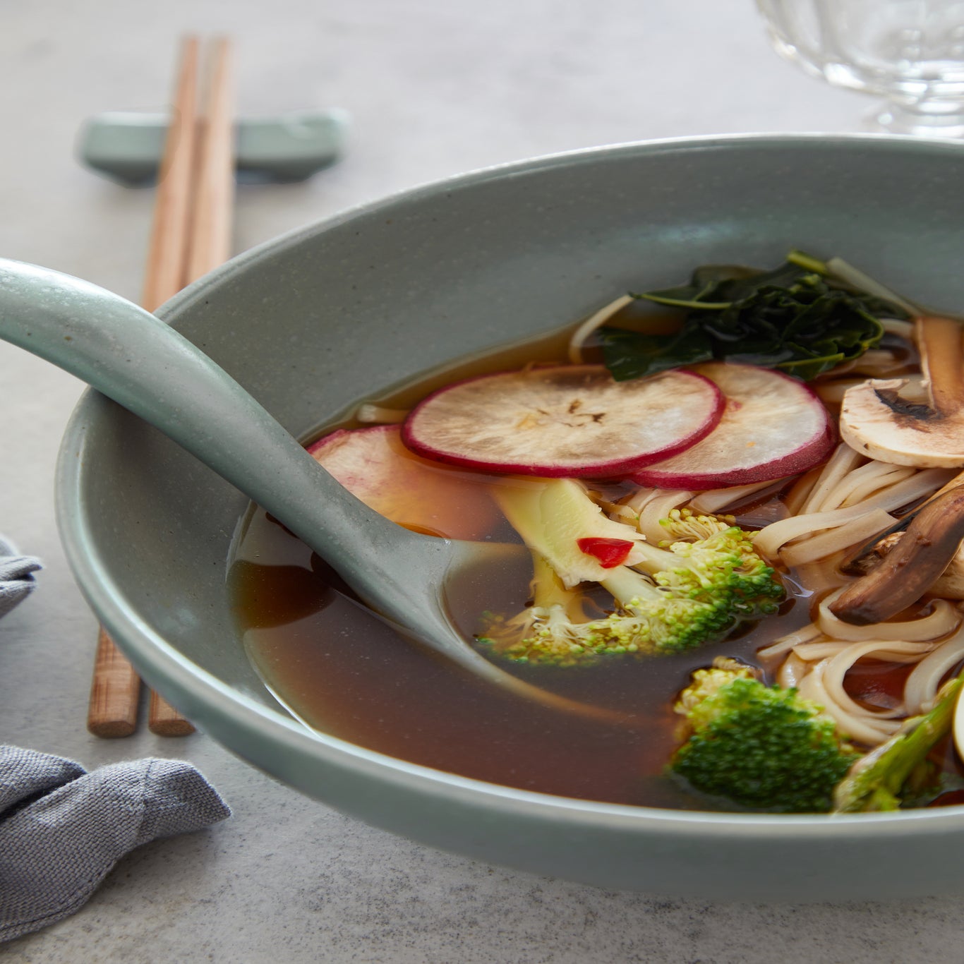 Bowl of soup with vegetables and noodles on a light surface