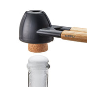 Cork and nutcracker with wooden handle and black rubber end, brand 'Gefu' visible, on a white background.