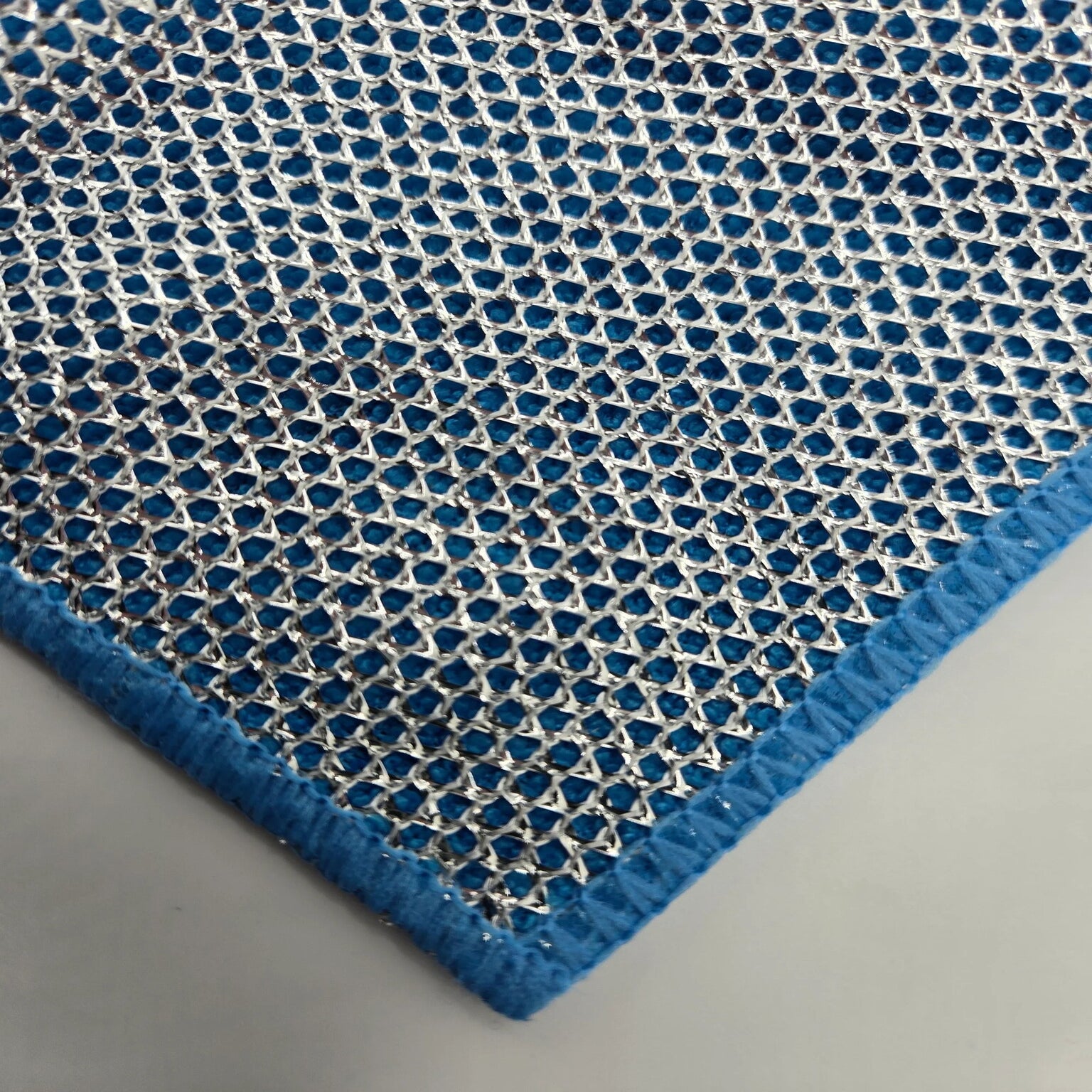 Blue textured cleaning cloth with a geometric pattern on a gray background