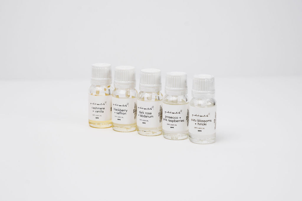 Set of small oil diffuser glass bottles with labels on a white background