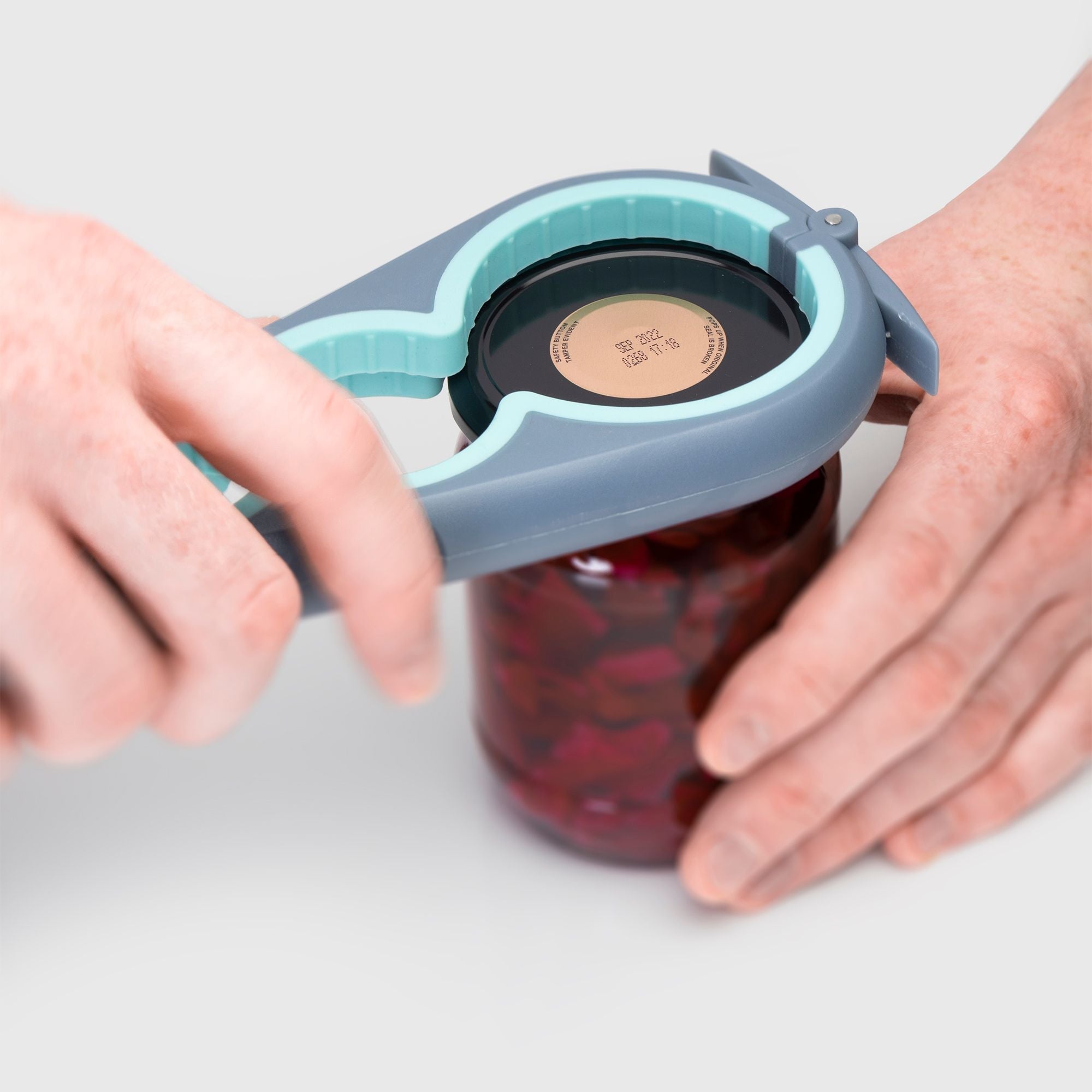 Person using a can opener on a jar with a white background