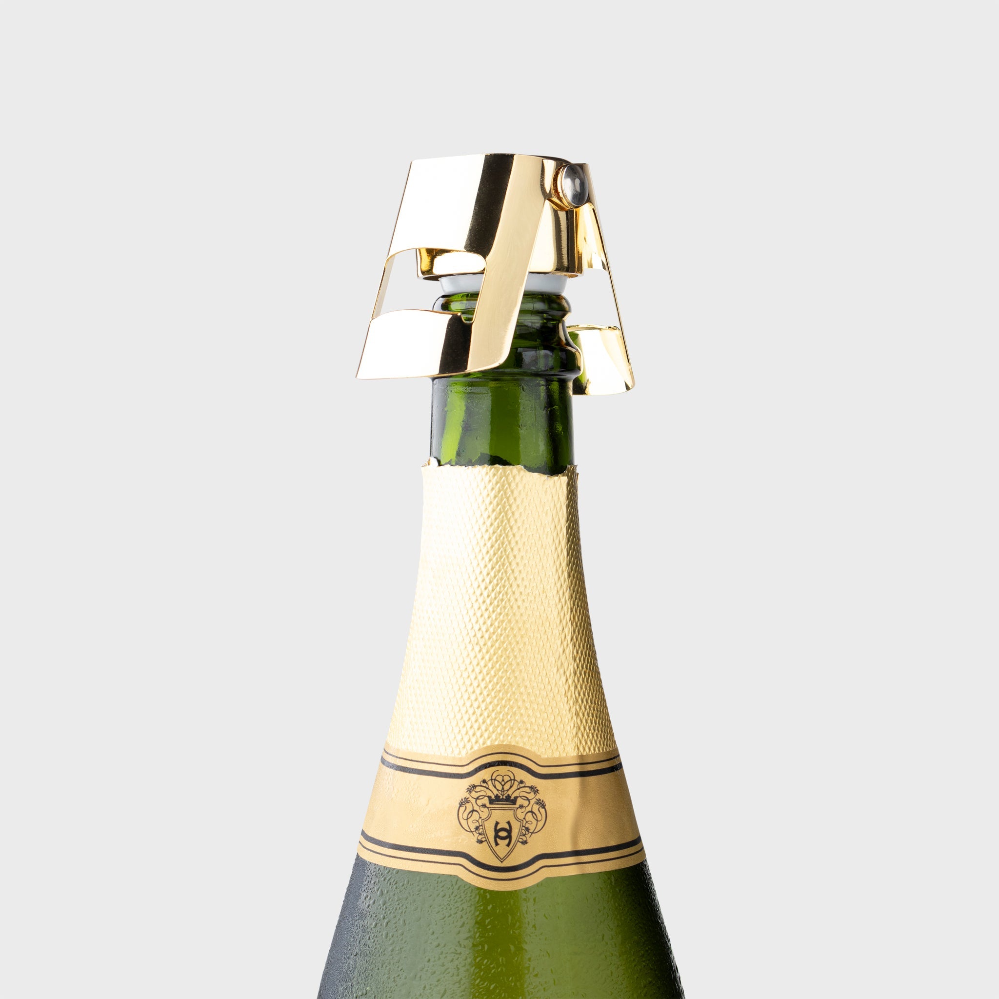 Green champagne bottle with gold foil top on a light gray background