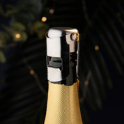 Gold bottle with a silver Taproom bottle stopper against a dark background