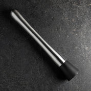 Black and silver cocktail muddler on a dark surface