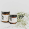 both sea salt surf candle brown jar white label black lid light background air plants at side