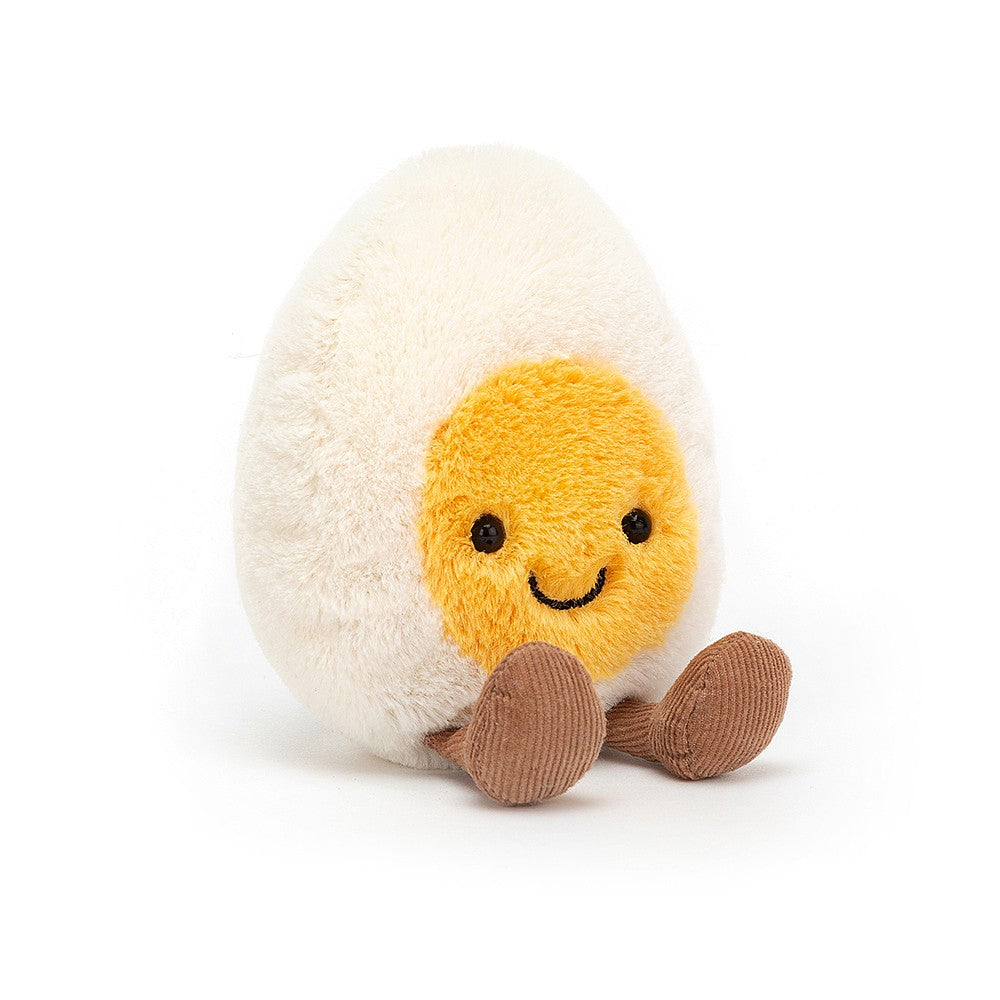 front view jellycat plush toy boiled egg with smiley face on yellow yolk and brown feet on white background