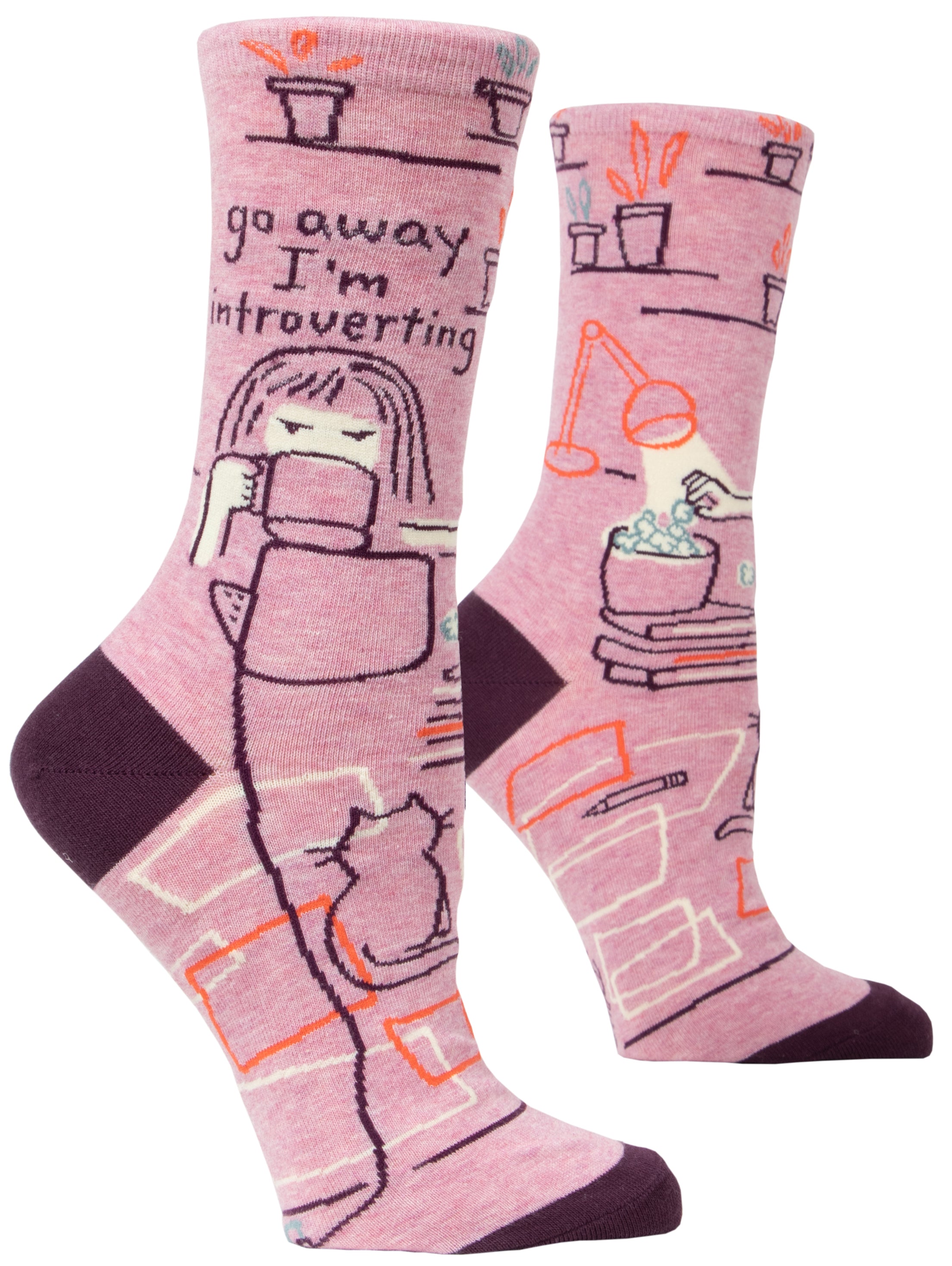 pink socks with cartoon of person as desk with popcorn books, lamp cat and plants on ankle it says go away i'm introverting 