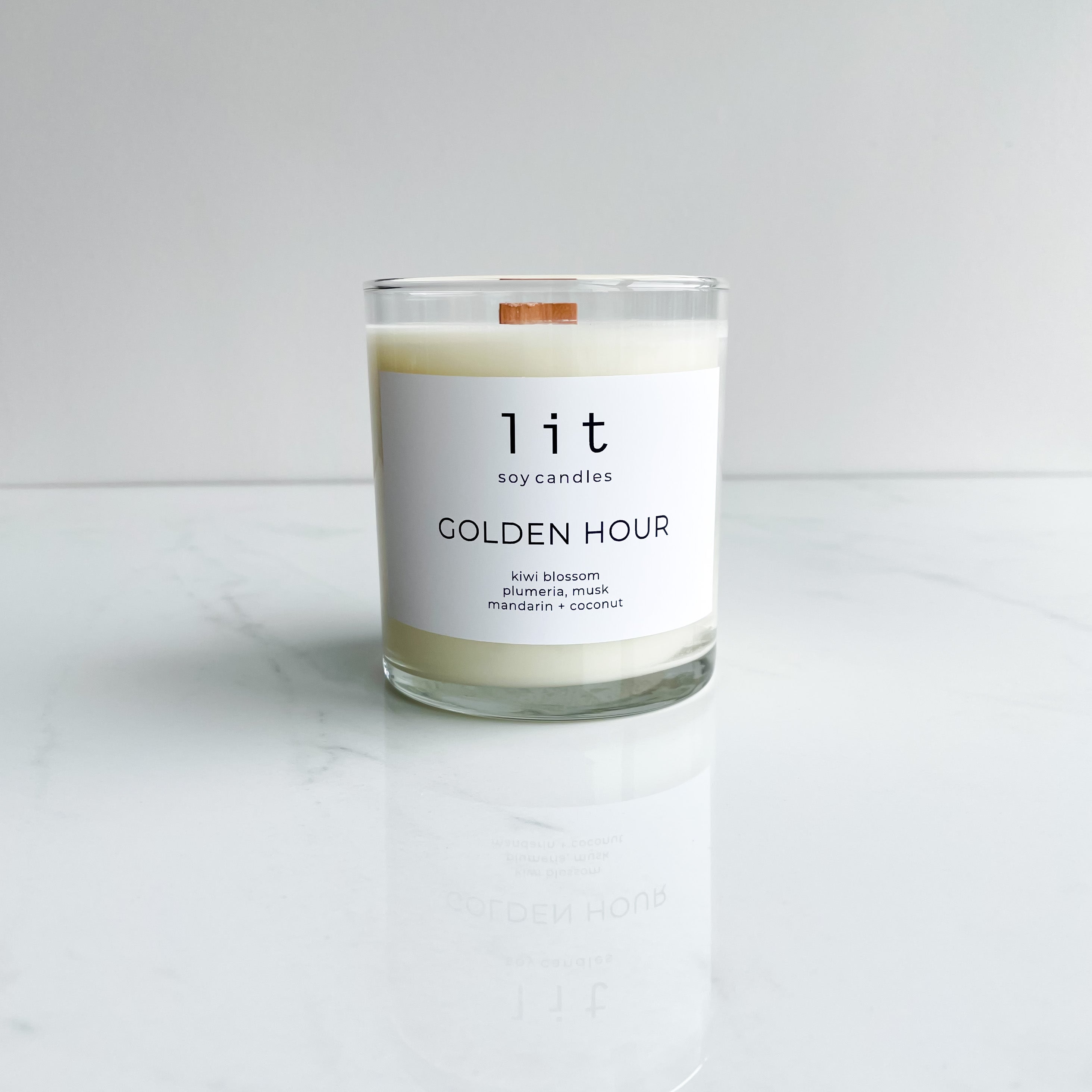 golden hour candle  clear glass jar wood wick white label on white marble table