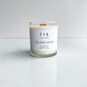 golden hour candle  clear glass jar wood wick white label on white marble table